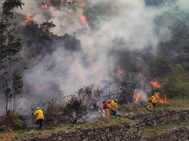Handout picture released by the Municipality of Machu Picchu showing firemen working to put out a fire in the bush surrounding the ruins of Llamakancha, a sector in the archaeological site of Machu Picchu, the Inca jewel of Peru's travel industry, in the highlands close to the city of Cusco, on June 28, 2022.  (Photo by Jesus TAPIA  /  Machu Picchu Municipality  /  AFP)  /  RESTRICTED TO EDITORIAL USE - MANDATORY CREDIT "AFP PHOTO  /  MACHU PICCHU MUNICIPALITY  /  JESUS TAPIA" - NO MARKETING - NO ADVERTISING CAMPAIGNS - DISTRIBUTED AS A SERVICE TO CLIENTS