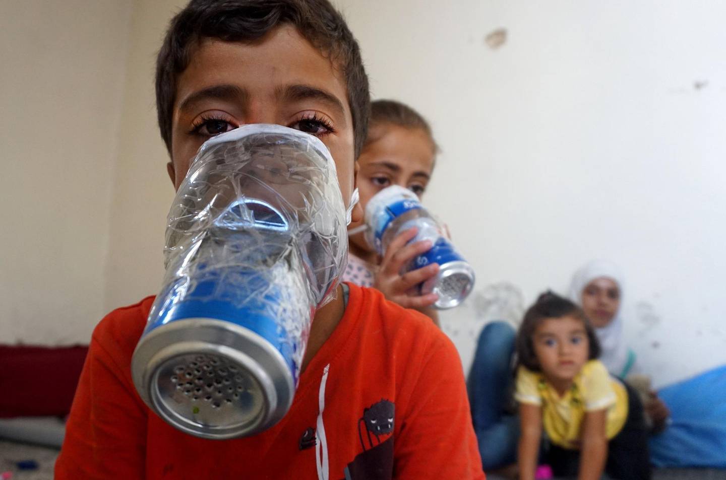 TOPSHOT - Children try improvised gas masks in their home in Binnish in Syria's rebel-held northern Idlib province as part of preparations for any upcoming raids on September 12, 2018. - The Syrian regime and its Russian ally are threatening an offensive to retake the northwestern province of Idlib, Syria's last rebel bastion. (Photo by Muhammad HAJ KADOUR / AFP)