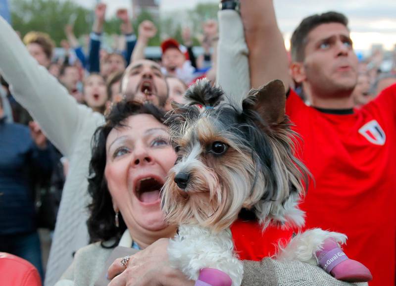 A woman screams holding a small dog as fans celebrate after Russia scored the third goal during the opening match of the 2018 World Cup, between Russia and Saudi Arabia, in the fan zone in Yekaterinburg, Russia. Vadim Ghirda / AP Photo