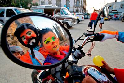 Clowns are reflected in a motorcycle's mirror. AFP