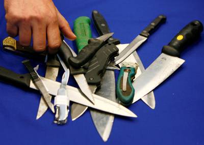 FILE PHOTO: A Metropolitan Police representative arranges knives, seized in recent operations, for photographers after a news conference about knife crime, at New Scotland Yard, in central London on May 29, 2008.    REUTERS/Luke MacGregor/File Photo