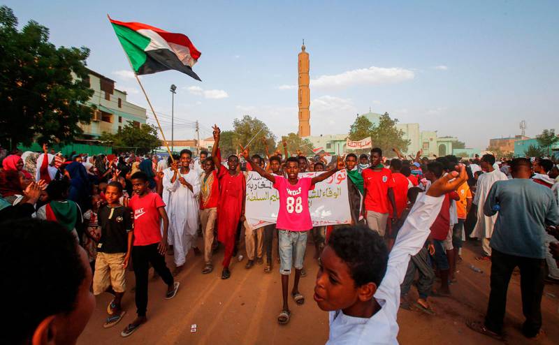 Sudanese people chant slogans and wave national flags as they celebrate after protest leaders struck a deal with the ruling generals on a new governing body, in the capital Khartoum's eastern district of Burri on July 5, 2019,  The deal, reached in the early hours of July 5 after two days of hard-won talks brokered by Ethiopian and African Union mediators, provides for the interim governing body to have a rotating presidency, as a compromise between the positions of the generals and the protesters. The blueprint proposes that a general hold the presidency for the first 18 months of a three-year transition, with a civilian taking over for the rest. / AFP / ASHRAF SHAZLY
