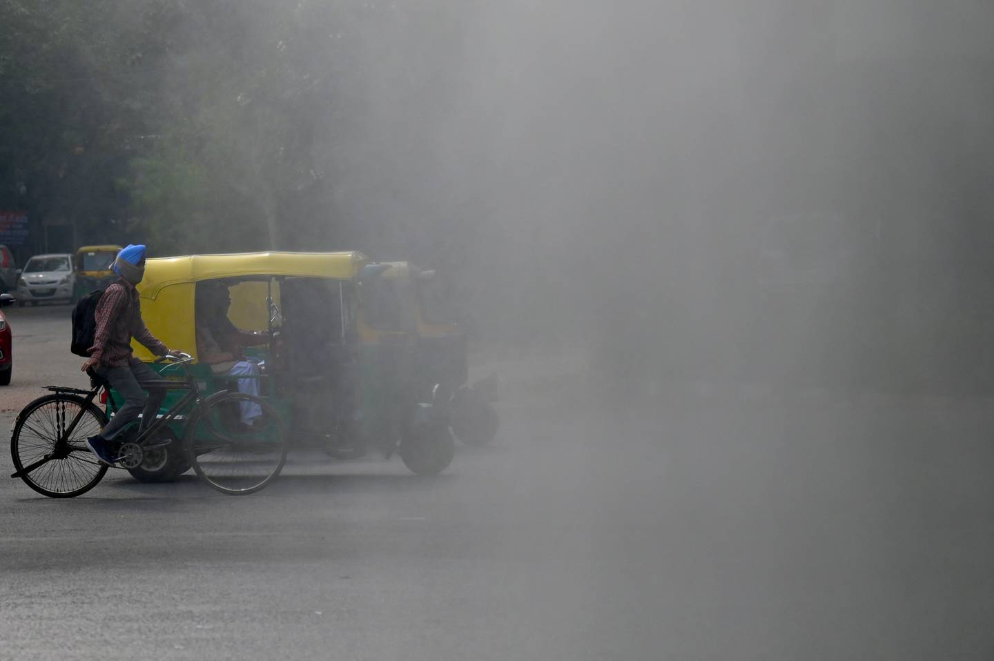 People move past a machine spraying mist, to tackle smoggy conditions, in New Delhi last year. AFP