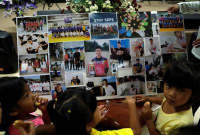 Children look at pictures as relatives and friends pray for the 12 schoolboys and their soccer coach. Reuters