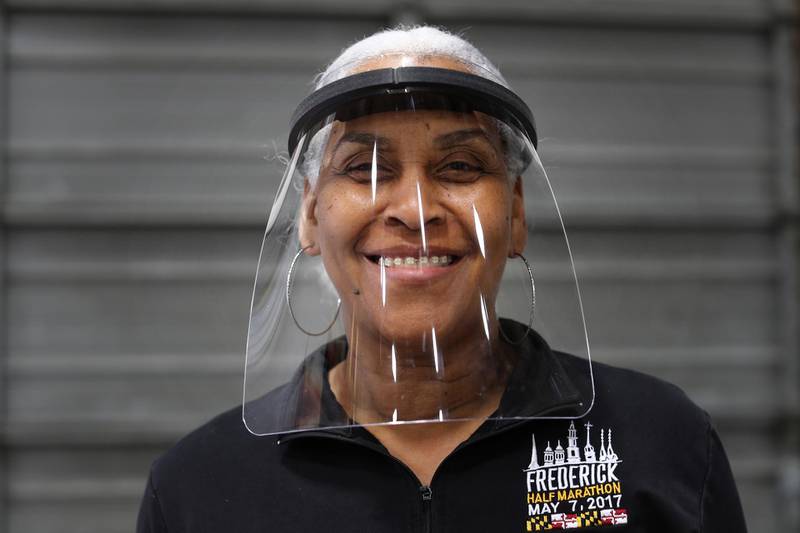 ELKRIDGE, MARYLAND - MARCH 31: U.S. Postal Service employee Angela Jones poses with a face shield she purchased from Hatch Exhibits so to protect her from the coronavirus March 31, 2020 in Elkridge, Maryland. As COVID-19 spread across the country, Hatch Exhibits -- which makes, stages, displays and pop-up exhibition booths -- furloughed its 23 employees after big projects were cancelled earlier this month. Then, a week ago, he and his staff found a way to repurpose their fabric and materials cutting machinery to quickly meet the demand for personal protection equipment for medical workers. After getting orders for tens of thousands of face shields and other gear, the company called back half its laid off employees and hopes to bring more back soon.   Chip Somodevilla/Getty Images/AFP
== FOR NEWSPAPERS, INTERNET, TELCOS & TELEVISION USE ONLY ==
