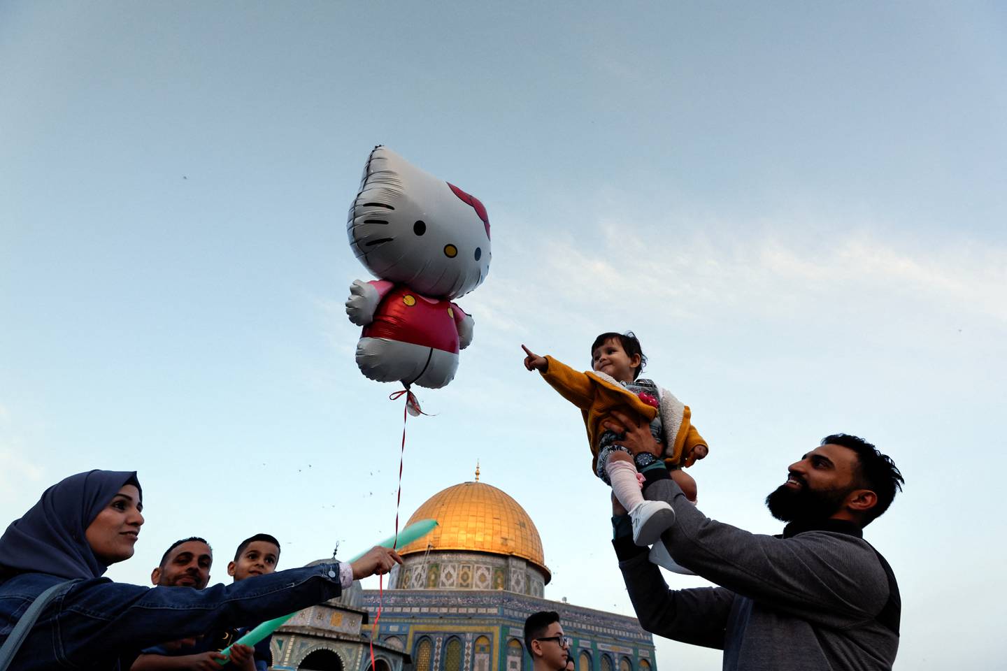 A man holds up a young girl during celebrations after the Eid prayers. Reuters