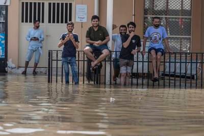Sitting on the fence, residents are all smiles despite pools of standing water forming on roads in Fujairah city. Antonie Robertson / The National

