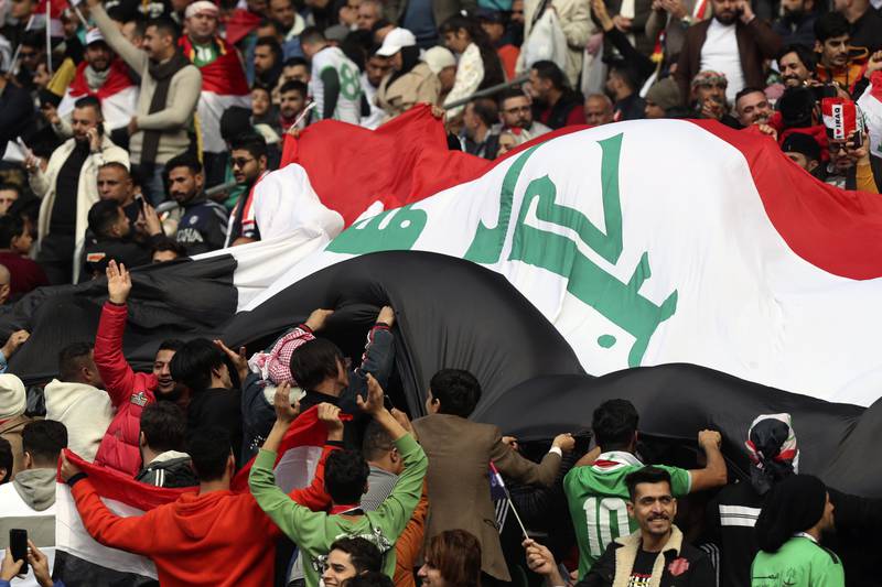 Fans cheering Iraq players with a huge flag at the semi-finals between Iraq and Qatar at Basra International Stadium. AP