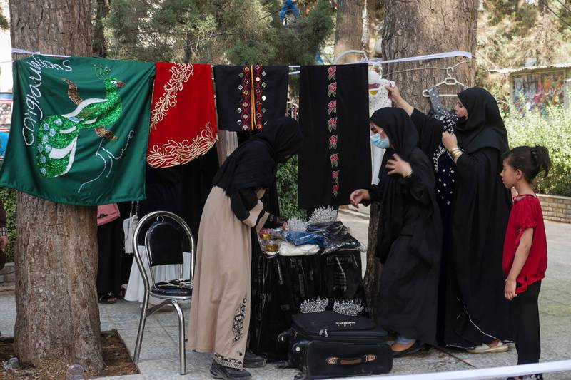 Women browse through garments and fabrics for sale in a stall at a women's handicraft market in Herat. AFP