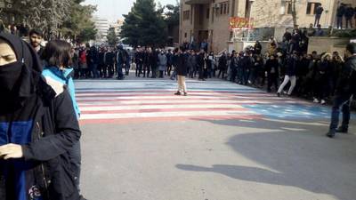 Students walk around, instead of across, US and Israeli flags at the Shahid Beheshti University in Tehran, Iran.  Reuters