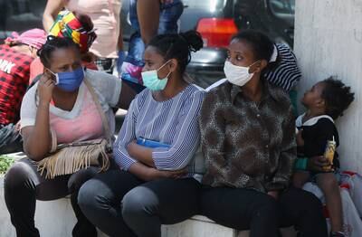 Ethiopian domestic workers wearing masks sit together with their belongings in front of the Ethiopian consulate in Hazmiyeh, Lebanon. Reuters