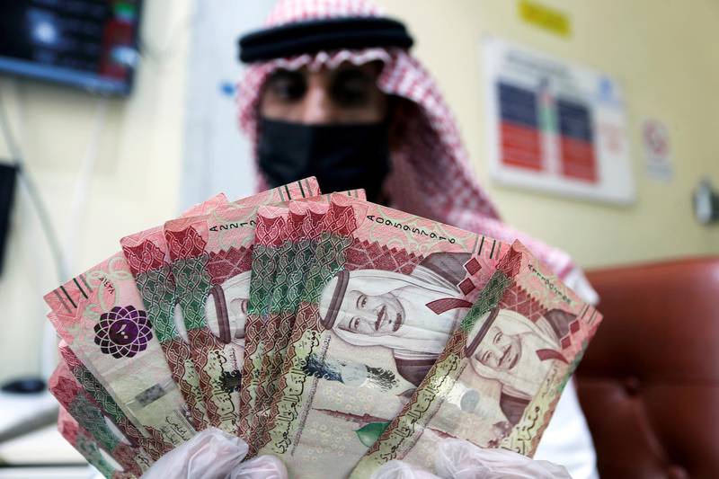 A Saudi money exchanger wears a protective face mask and gloves as he counts Saudi riyal currency at a currency exchange shop in Riyadh, Saudi Arabia March 10, 2020. Reuters
