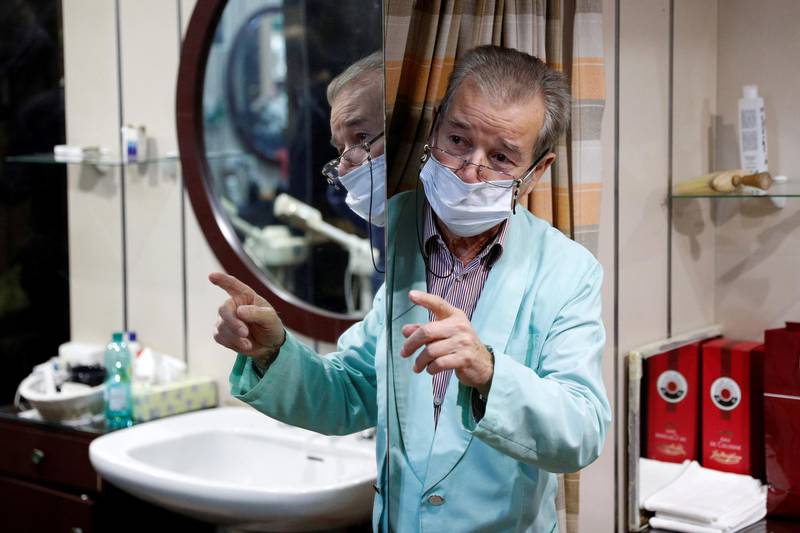 Barber Luigi Pinzo, 80, gestures to a client two days before closing his salon after 60 years because of a lack clients and fear of the coronavirus disease in Rome, Italy. Reuters