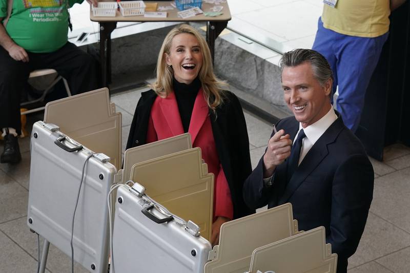 Mr Newsom and Ms Siebel Newsom laugh as they vote in Mr Newsom's re-election campaign. AP