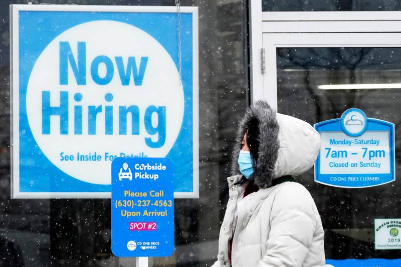 FILE - In this Feb. 6, 2021, file photo, a woman walks past a "Now Hiring" sign displayed at a CD One Price Cleaners in Schaumburg, Ill. U.S. employers added a surprisingly robust 379,000 jobs in February in a sign the economy is strengthening as virus cases drop, vaccinations ramp up, Americans spend more and states ease business restrictions. (AP Photo/Nam Y. Huh, File)