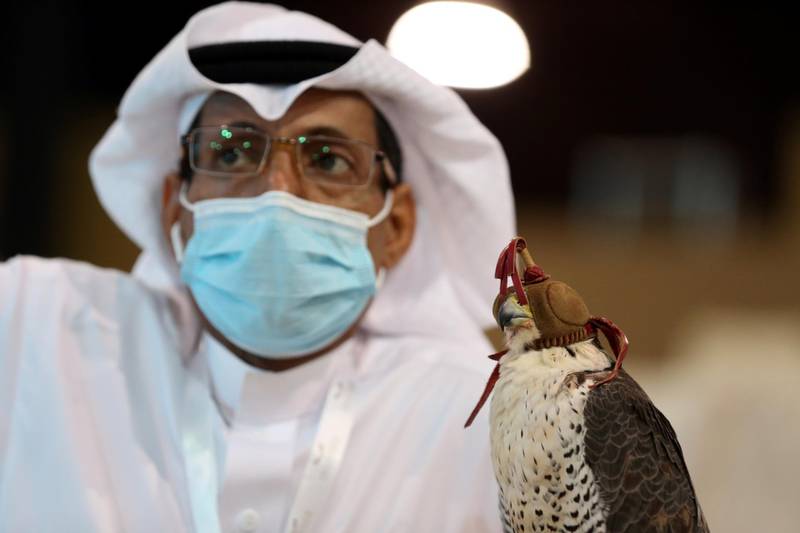 A Saudi man wearing a face mask waits for his turn with his falcon at Saudi Falcons Club Auction in Riyadh. Ahmed Yosri / Reuters