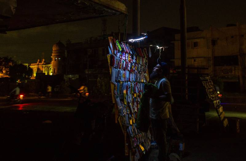 A vendor sells decorations for motorbike registration plates under an emergency light at his makeshift stall in Karachi. All photos: Bloomberg