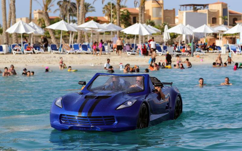 Karim Amin, one of the Egyptians who invented this vehicle that can drive on water, gives bathers at Porto Marina in Alexandria a closer look at the water car. Reuters