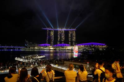 People watch a light show, as the traditional New Year's Eve fireworks are cancelled, off Marina Bay in Singapore. Reuters