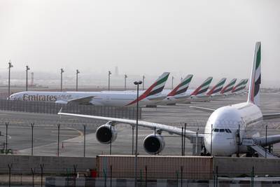 An Airbus SE A380-800, right, and a line of Boeing Co. 777-300 aircraft, operated by Emirates, stand in a parking zone at Dubai International Airport.