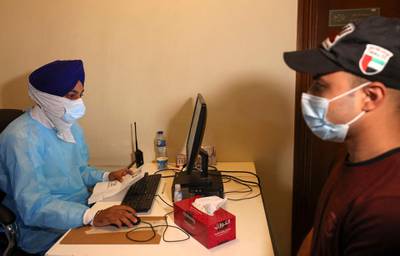 A Sikh healthcare worker registers a man for vaccination at the Guru Nanak Darbar gurudwara (Sikh temple) in Dubai on Saturday. Karim Sahib / AFP