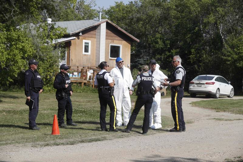 Forensics officials and police officers speak outside the crime scene where stabbing victim Wes Petterson was found, in Weldon, Saskatchewan. AFP