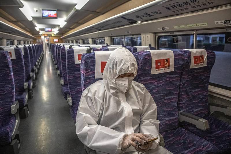 A passenger wearing protective clothing sits in the first official train departing from Wuhan.  EPA