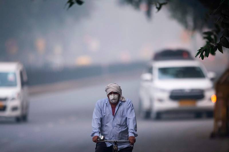 A man wearing protective face mask rides a bicycle along a street in smoggy conditions in New Delhi on November 4, 2019. Millions of people in India's capital started the week on November 4 choking through "eye-burning" smog, with schools closed, cars taken off the road and construction halted. / AFP / Jewel SAMAD
