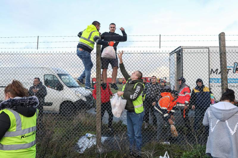 Volunteers distribute fresh food and supplies over a perimeter fence to truck drivers at Manston airport in Manston, U.K. Routes to Dover, Britain's busiest cross-channel port, have been choked for days after France shut its border with Britain, blaming an outbreak of a novel strain of the coronavirus. Bloomberg