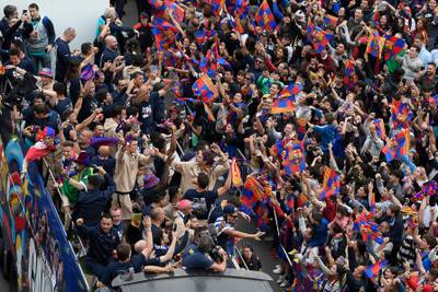 The players and staff of Barcelona men's football team parade aboard an open-top bus. AFP