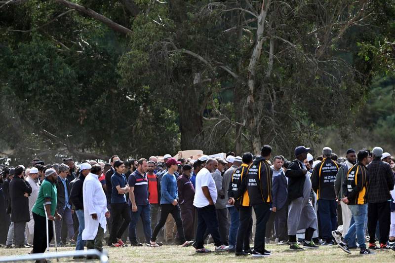Mourners carry coffins of the Christchurch mosques massacre victims at Memorial Park Cemetery during the funeral ceremony in Christchurch on March 20, 2019. As the first bodies of the Christchurch mosque shooting victims were returned to grieving families, Muslim volunteers from across New Zealand and Australia descended on the small town to help in the burial process. Islamic custom dictates that people have to be buried as soon as possible, but the scale and devastation of March 15's massacre -- that saw 50 killed in the usually quiet southern New Zealand city -- has delayed the handover of bodies to next of kin. / AFP / Anthony WALLACE
