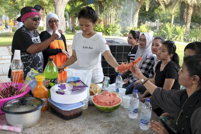 DUBAI, UNITED ARAB EMIRATES. 21 AUGUST 2018. Residents of Dubai enjoy the Eid break. Riana Rabox (Indonesia) hands out watermelon out to her friends during a barbeque in Zabeel parkt. (Photo: Antonie Robertson/The National) Journalist: None. Section: National.