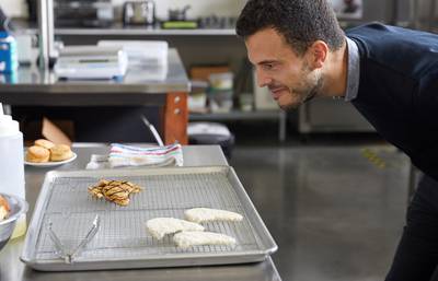 An employee of Eat Just looks at grilled fillet made from lab-grown cultured chicken developed by Eat Just. Eat Just via Reuters