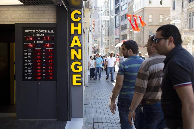 Pedestrians stop to look at currency rates advertised at an international currency exchange bureau on Stiklal Avenue in Istanbul on Thursday, July 21, 2016. Danielle Villasana / Bloomberg