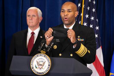 Holding up a mask, US Surgeon General Jerome Adams, right, urges the public to use masks as he speaks during a news conference with Vice President Mike Pence in Rockville, Mayland this week. AP Photo
