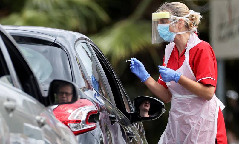FILE PHOTO: A medical worker takes a swab sample in a drive-thru testing centre, following a spike in cases of the coronavirus disease (COVID-19) to visitors of a pub in Stone, Britain, July 29, 2020. REUTERS/Carl Recine/File Photo