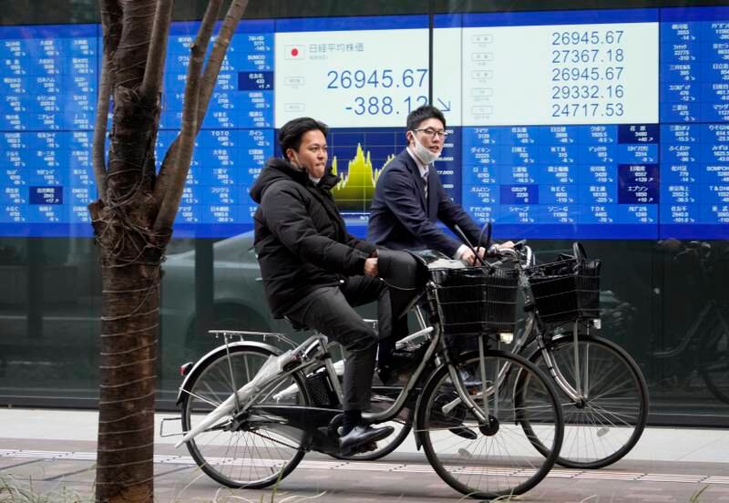 Businessmen cycle past a stock market indicator board in Tokyo, Japan. The Tokyo stock market fell amid concerns over the confidence crisis in banks in the US and Europe. EPA