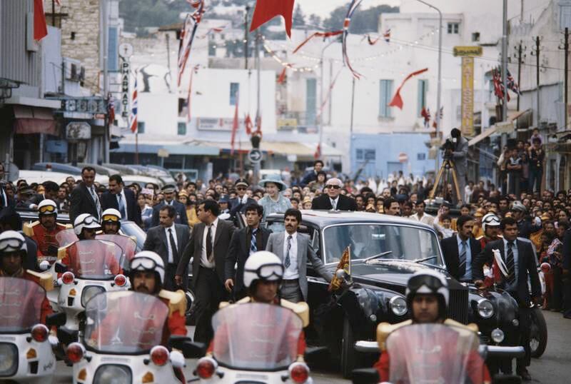 The queen drives through Tunis with Tunisian President Habib Bourguiba during a state visit in October 1980. Getty