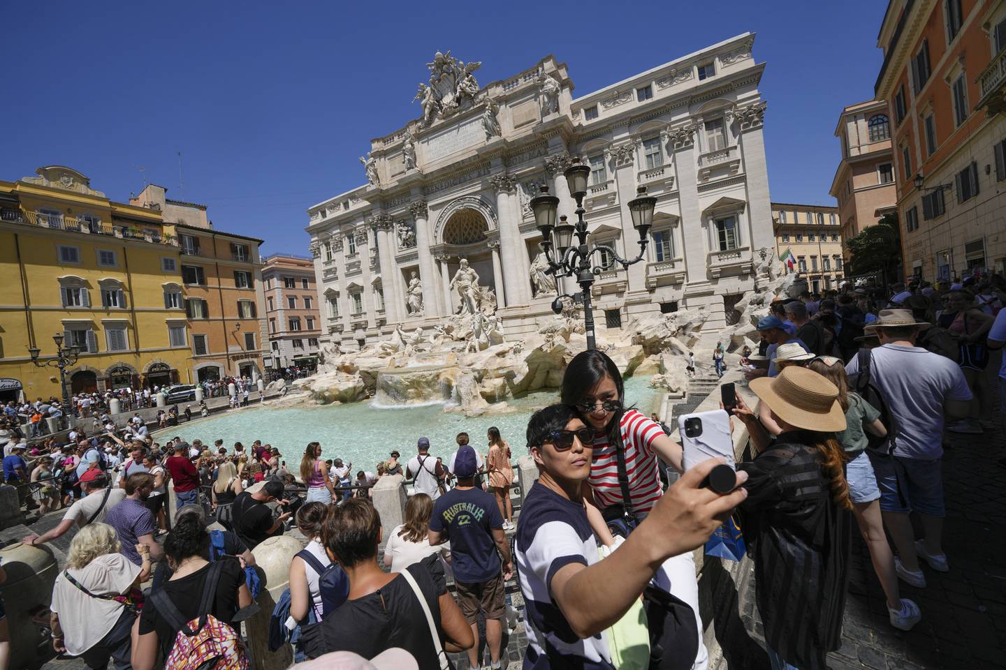Tourists take a selfie in front of the Trevi Fountain, in Rome. AP