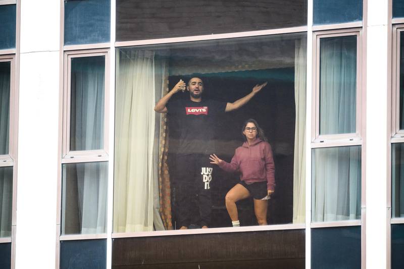 A couple gesture to the media from their room at the Radisson Blu Edwardian hotel, near Heathrow Airport. Getty Images