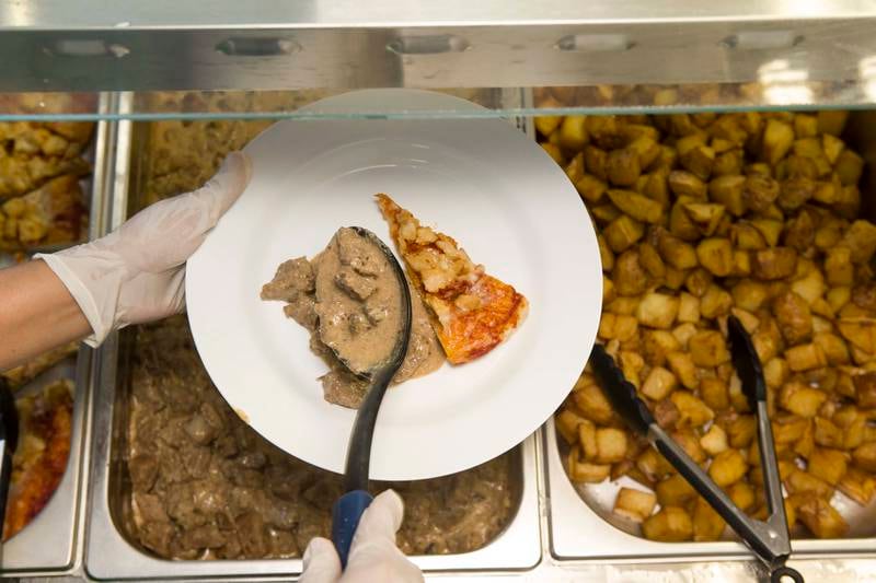 ABU DHABI, UNITED ARAB EMIRATES, SEPTEMBER 24, 2014. Slices prepares fresh, healthy, home cooked style meals with nutrional value on site for Schools in the UAE. A member of Slices staff dishes up a students plate in the school cafeteria kitchen at the Brighton College in Al Ain. (Photo: Antonie Robertson/The National) Journalist: Dana Moukhallati. Section: National.