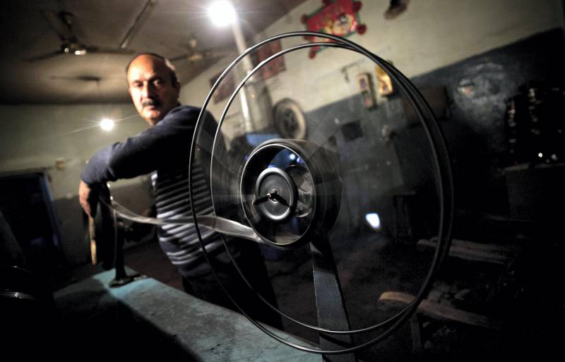 Cinema operator Rassoul winds a roll of film as he shows a bollywood movie Cinema Park theatre in the Shar-e-Naw district of Kabul on May 1, 2012. The Cinema Park theatre  has 544 seats and features Indian films mostly running two times a day in the morning.  AFP PHOTO/ JOHANNES EISELE (Photo by JOHANNES EISELE / AFP)