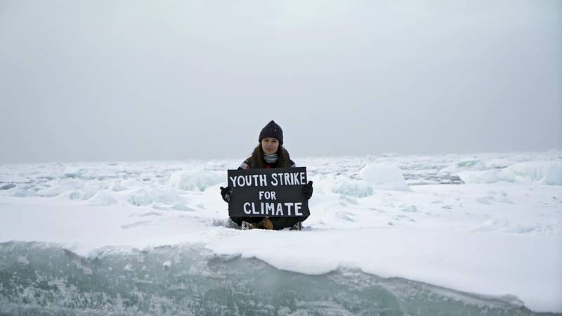 Environmental activist and campaigner Mya-Rose Craig, 18, holds a cardboard sign reading "youth strike for climate" as she sits on the ice floe in the middle of the Arctic Ocean, hundreds of miles above the Arctic Circle, September 20, 2020. REUTERS/Natalie Thomas