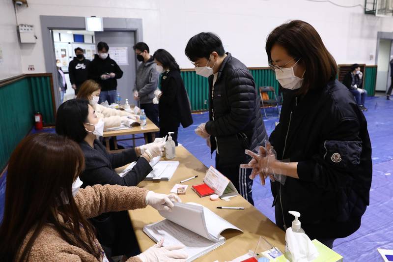 South Koreans wear masks and plastic gloves as they queue up to cast their ballots for the Parliamentary election in Seoul, South Korea. Getty