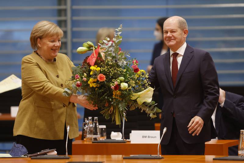 Mrs Merkel receives a bouquet of flowers from Olaf Scholz as she arrives for probably her last weekly cabinet meeting on November 24. Getty Images