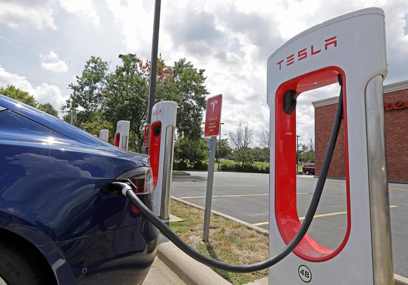 FILE - In this July 19, 2019 file photo, a Tesla vehicle charges at a Tesla Supercharger site in Charlotte, N.C. Tesla owners can now buy insurance policies from the electric car company in what may be an essential step toward it selling driverless vehicles. The company says itâ€™s now selling policies in California and will go nationwide at an undisclosed date. (AP Photo/Chuck Burton, File)