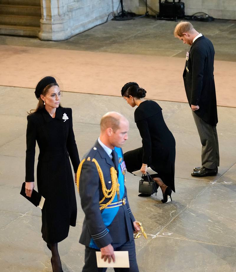 Meghan, Duchess of Sussex, curtsies to the coffin of Queen Elizabeth II, next to her husband Prince Harry, inside the Palace of Westminster on September 14, 2022. AFP