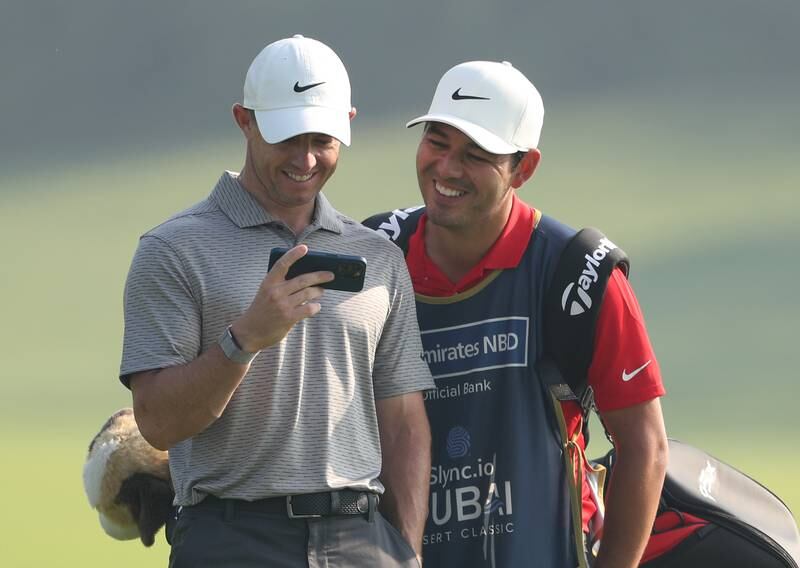 Rory McIlroy of Northern Ireland watches his phone with his caddie Harry Diamond.
