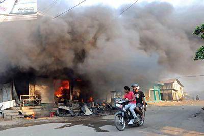 Residents ride a motorcycle past a burning building in riot-hit Meiktila, central Myanmar. At least 36 people have been killed in anti-Muslim rioting since Wednesday. Soe Than Win / AFP Photo