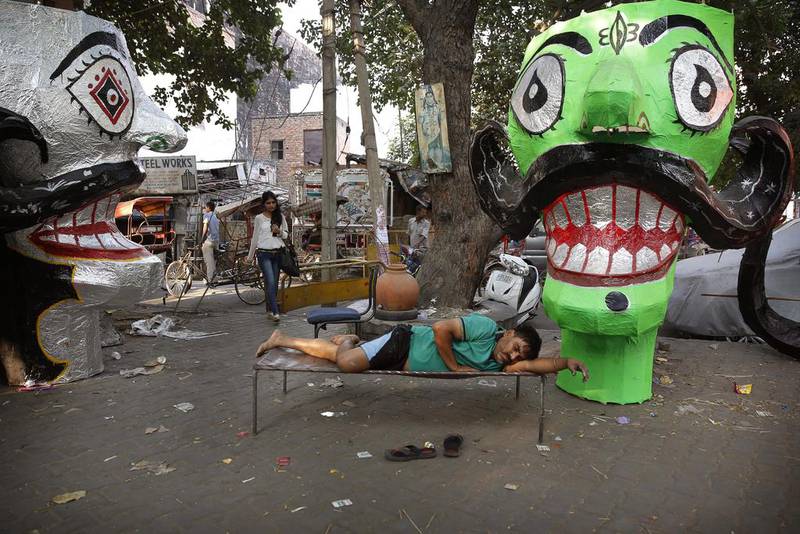 An artist rests on a cot after preparing effigies of the ten-headed demon god Ravana in preparation for the upcoming Dessehra festival in New Delhi.  Manish Swarup / AP Photo